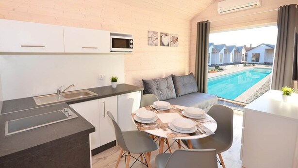 A compact kitchen with a dining area, a built-in microwave, and a view of a swimming pool. - Holiday Home Near Bukowo Lake and Beach (Darlowo)