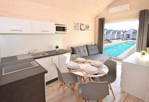 A compact kitchen with a dining area, a built-in microwave, and a view of a swimming pool. - Holiday Home Near Bukowo Lake and Beach (Darlowo)