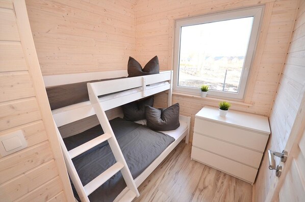 A compact room with a bunk bed, a small bedside table with a plant, and a window with a view of the outdoors. - Holiday Home Near Bukowo Lake and Beach (Darlowo)