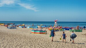 A beach with people, umbrellas, and a lifeguard tower. - Holiday Home Near Bukowo Lake and Beach (Darlowo)