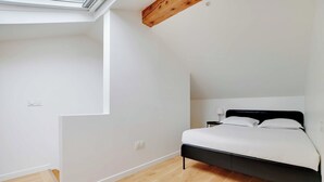 Une chambre avec un puits de lumière, un lit et une table de chevet.
