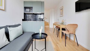 Un espace de vie compact comprenant un coin cuisine, un coin repas et un coin salon.