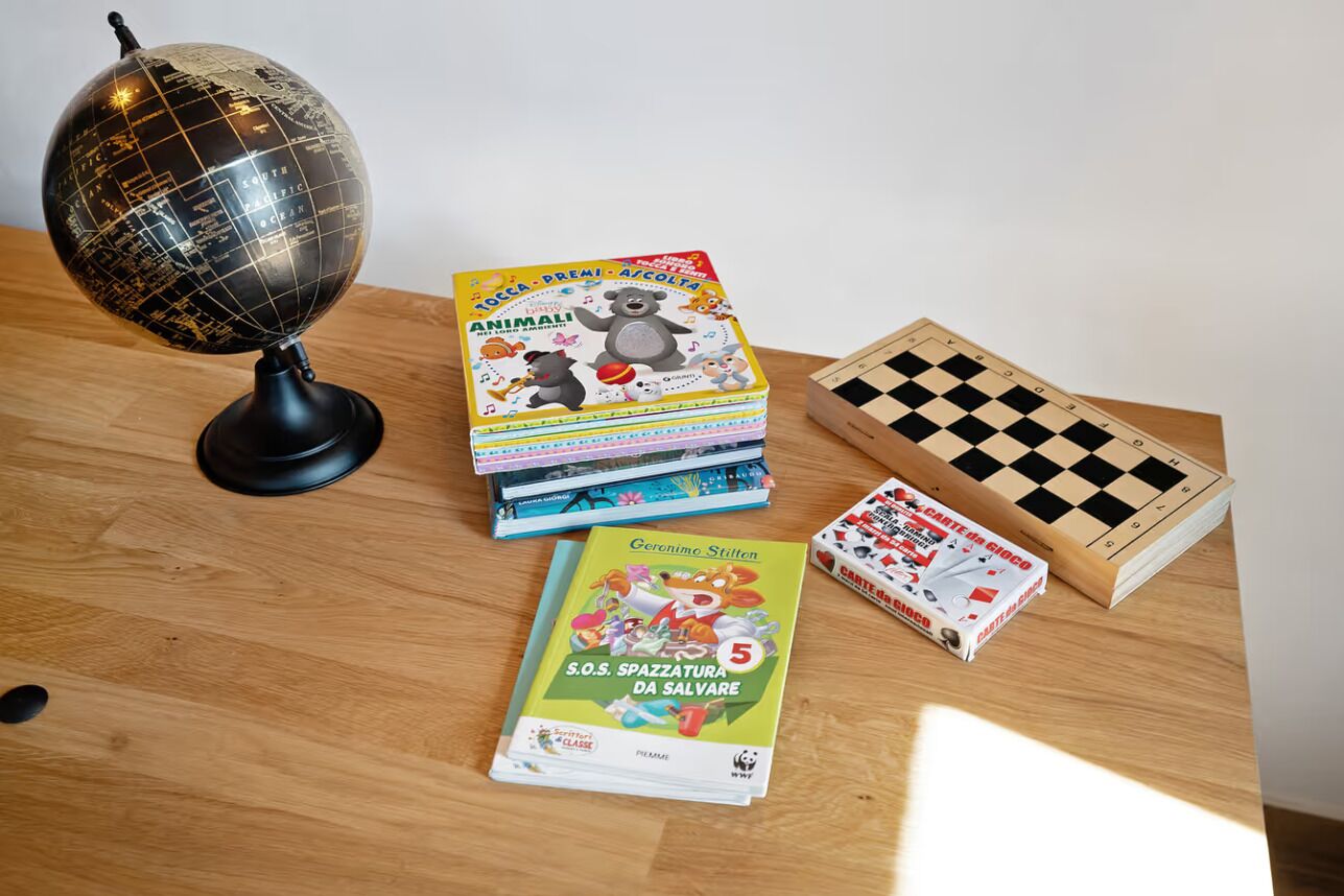 Une table en bois sur laquelle on trouve un globe terrestre, des livres pour enfants et un jeu d’échecs.
