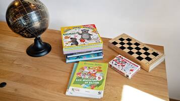 Une table en bois sur laquelle on trouve un globe terrestre, des livres pour enfants et un jeu d’échecs.