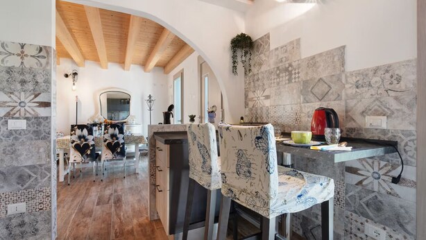 Uma cozinha com ilha central, vigas de madeira e azulejos estampados.