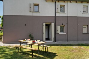 A modern building with a flat roof, a patio area with a wooden table and benches, and a door leading to an interior space. - At the Court of the Angel, a welcoming house with free private parking (Chirignago-Zelarino)