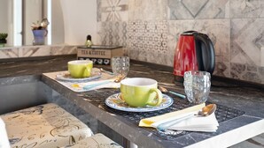 Uma bancada de cozinha com uma cafeteira, duas xícaras e um copo.