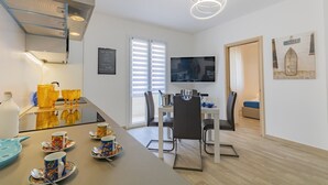 Een moderne keuken met een eethoek, een aan de muur bevestigde televisie, en een trap die naar een ander niveau leidt.