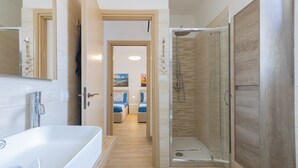 Een moderne badkamer met een badkuip, een glazen douche en een houten wastafelmeubel.