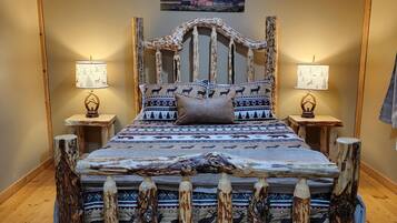 A wooden-framed bed with a patterned bedspread, two bedside lamps, and a painting on the wall.