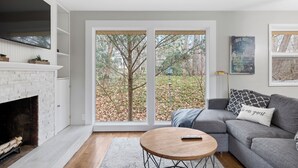A living room with a fireplace, a gray sofa, a round coffee table, and a large sliding glass door leading to a yard.