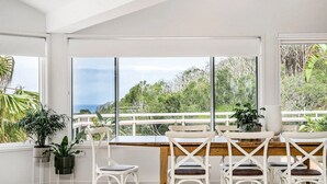 A bright room with large windows, white furniture, and potted plants. - Byron Pacific Vista - Family Fun with Pool (Byron)