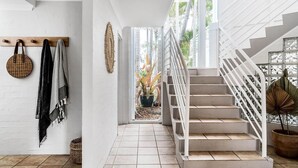 A staircase with white railings leading to an outdoor area with plants and a view of palm trees. - Byron Pacific Vista - Family Fun with Pool (Byron)