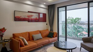 Un salon moderne avec une grande fenêtre, un canapé, une table basse et un tableau accroché au mur.