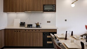 Une cuisine moderne avec des meubles en bois, un four encastré et un coin repas avec une table dressée pour deux personnes.