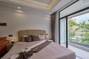 A modern hotel room with a large bed, a nightstand with a lamp, and a view of greenery through a large window.