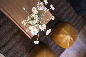 A top-down view of a room with a wooden table, a brown rug, and two round, gold-colored ottomans. - Little Blue House 1 - Daniel&Jacob's Premium Apartments (Copenhagen)
