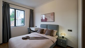 A modern hotel room with a bed, desk, and chair.