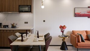 A modern kitchen with a built-in microwave, a dining table set for four, and a sofa in the living area.
