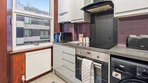 Cocina compacta equipada con microondas, horno y lavavajillas. Una ventana ofrece vistas al exterior.