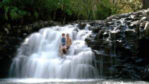 A waterfall with two people sitting on rocks. - Easy Campers Maui - Paradise Jays Maui Island Breeze (Kihei)