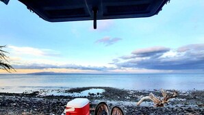 A beach view from inside a vehicle with a cooler, water bottles, and a red container on the ground. - Easy Campers Maui - Paradise Jays Maui Island Breeze (Kihei)
