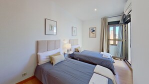 A hotel room with two beds, a bedside table with a lamp, and a window with curtains. - Spectacular apartment in Cuatro Caminos (Madrid)