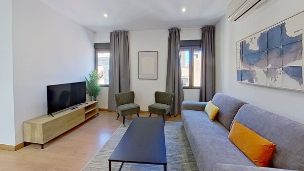 A modern living room with a flat-screen TV, two armchairs, a sofa, and a coffee table. - Spectacular apartment in Cuatro Caminos (Madrid)