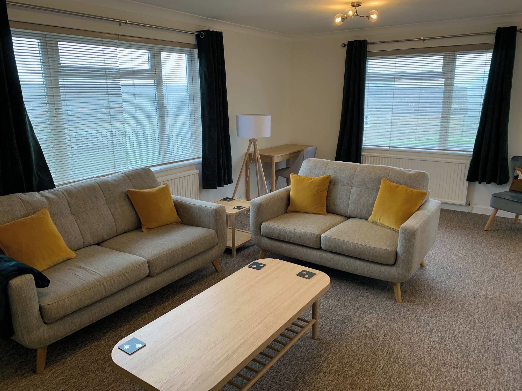 A modern living room with two sofas, a coffee table, and a lamp.
