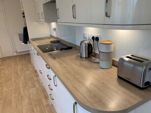 A modern kitchen with white cabinets, a stainless steel kettle, a toaster, and a kettle on the countertop.
