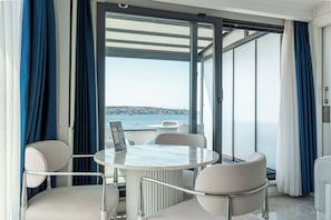 A modern balcony with a round table and chairs, overlooking a body of water and a distant cityscape. - Elite World Homes Istanbul Bosphorus (Istanbul)