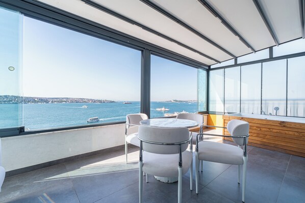 A modern dining area with a view of the sea and boats.