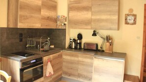 A compact kitchen with wooden cabinets, a built-in oven, and a coffee maker.