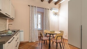 A compact kitchen with a dining area, featuring a round table and chairs, a built-in oven, and a window with curtains. - Casa agli Eremiti by Wonderful Italy (Palermo)