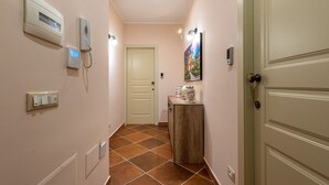 A hallway with a light switch, a thermostat, a phone, a door, and a cabinet with decorative items. - Casa agli Eremiti by Wonderful Italy (Palermo)