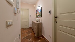 A hallway with a door, a wall-mounted phone, a light switch, and a cabinet with decorative items. - Casa agli Eremiti by Wonderful Italy (Palermo)