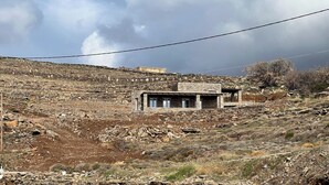 A remote, rustic building with a stone facade, situated on a rocky hillside. - Tzia Stone Modern Studio with Sea View (Kea)