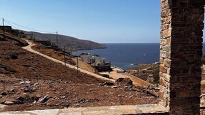A stone structure with a view of a coastal landscape, including a road and buildings. - Tzia Stone Modern Studio with Sea View (Kea)
