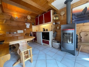 A cozy wooden cabin with a kitchen area featuring a stove, cabinets, and a dining table.