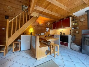 A wooden interior with a kitchen, dining area, and a staircase.