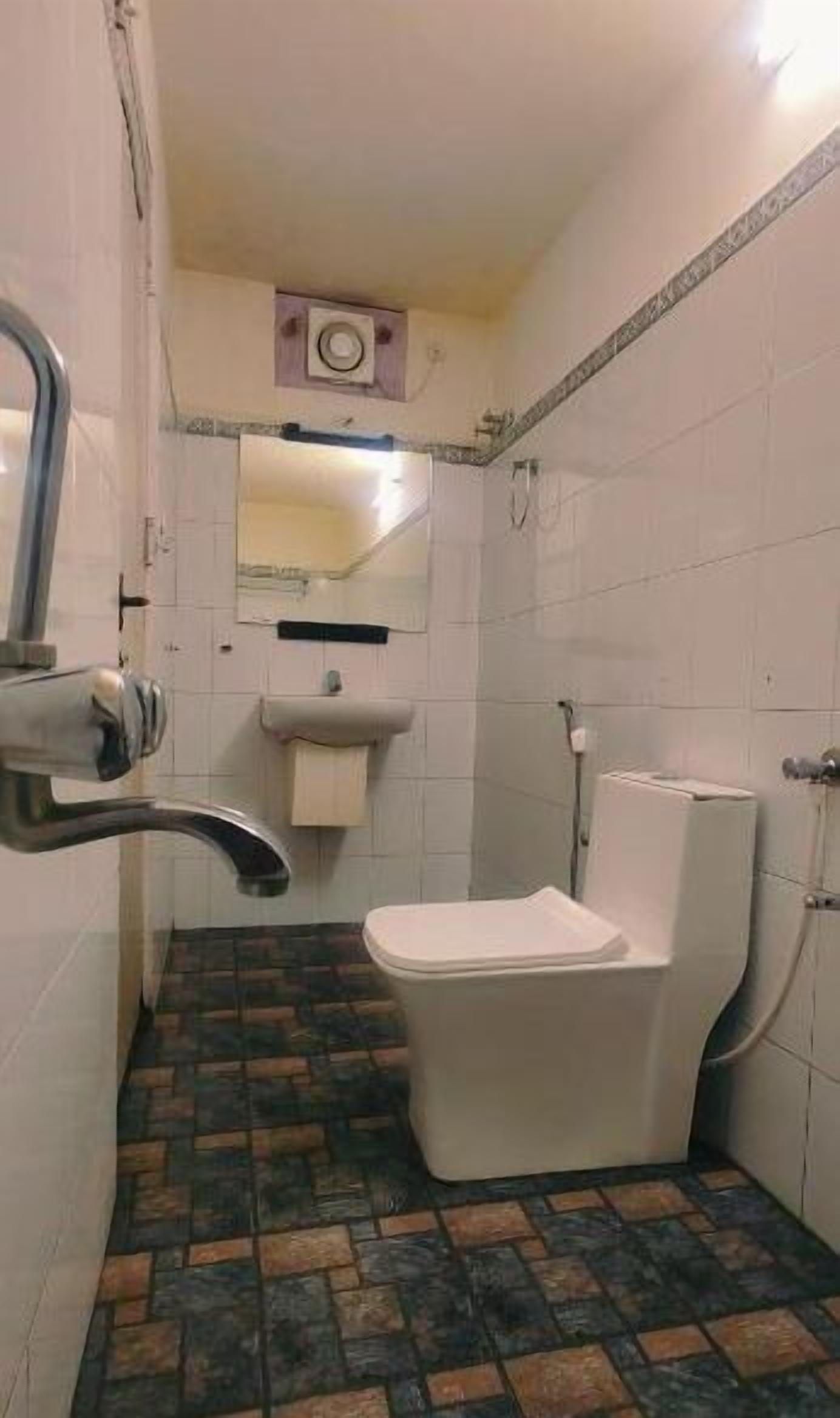 A small bathroom with a toilet, sink, and shower.