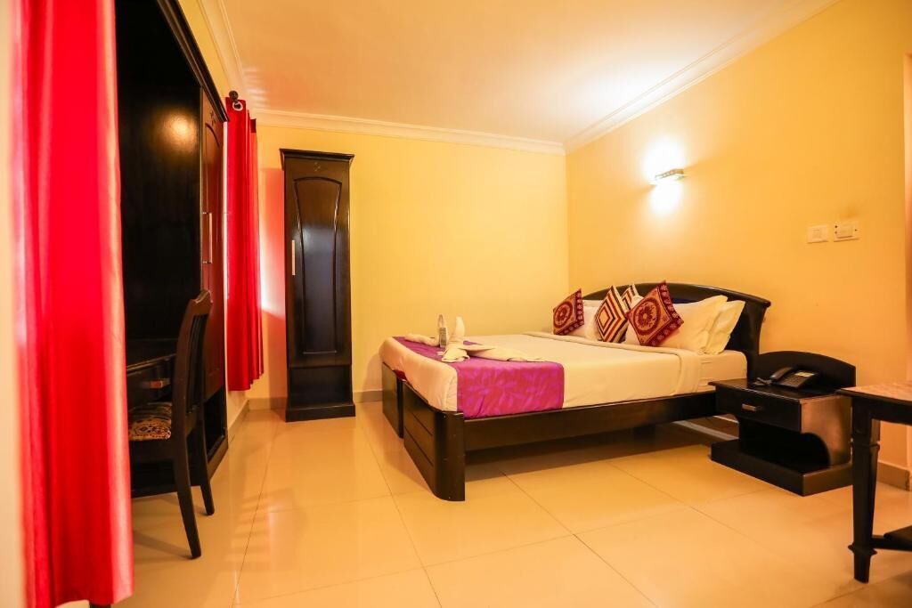 Una habitación de hotel con cama, mesita de noche y una silla.