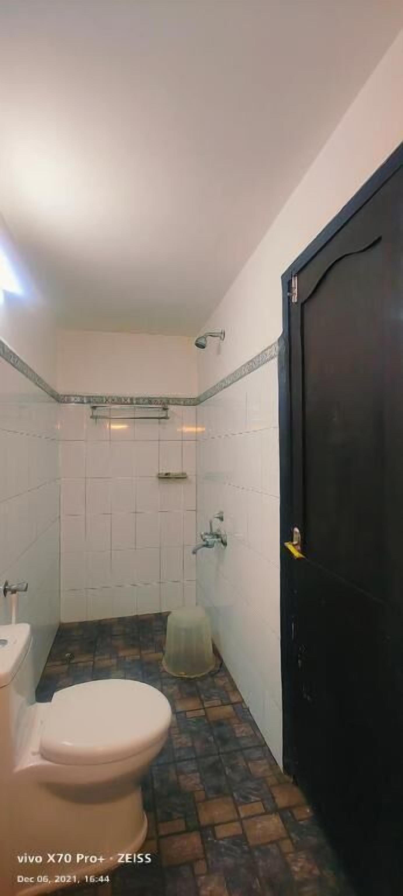 A bathroom with a toilet, shower, and a black door.