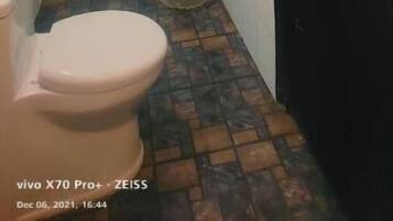 A bathroom with a toilet, shower, and a black door.