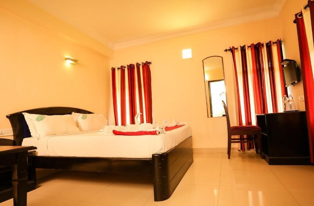 A hotel room with a bed, a desk, a chair, and a TV.