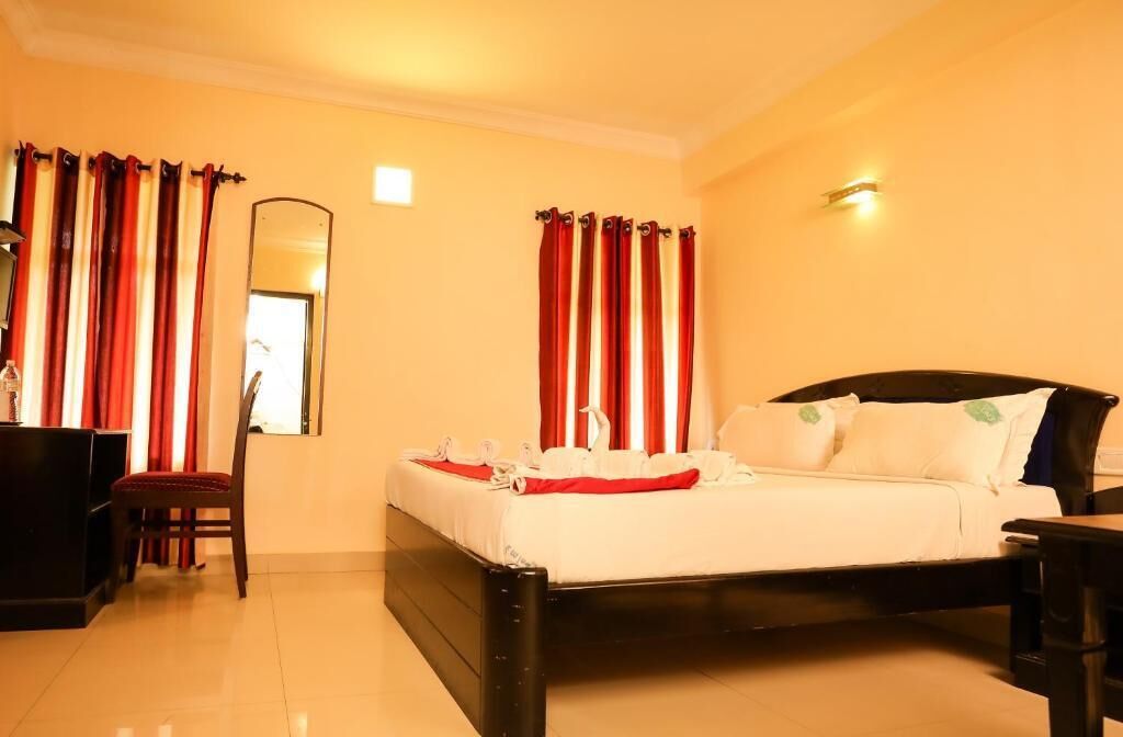 A hotel room with a bed, a chair, a desk, and a mirror.