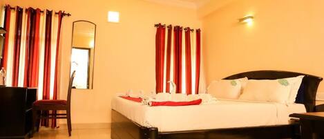 A hotel room with a bed, a chair, a desk, and a mirror.
