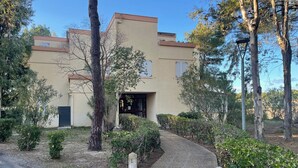 A building with a beige facade, a paved entrance, and surrounding greenery. - Argelès T2 beach, park, parking, 4 pers (Argelès-sur-Mer)