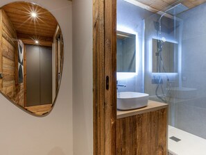 A modern bathroom with a wooden vanity, a round mirror, and a glass-enclosed shower. - Premium apartment, 4 ppl, wifi (Val-d'Isère)