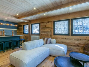A cozy cabin interior with a wooden interior, a sofa, a dining table, and a bar area.